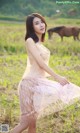 A woman in a pink dress standing in a field with a horse.