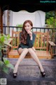 A woman sitting on a wooden swing with her legs crossed.