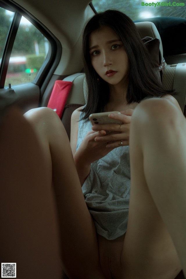 A woman sitting in the back seat of a car looking at her phone.
