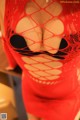 A woman in a red fishnet dress posing for the camera.