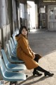 A woman sitting on a row of blue chairs.