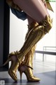 A close up of a woman's legs wearing gold boots.