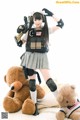 A woman in a military uniform holding a gun and a teddy bear.