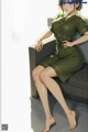 A woman in a green dress sitting on a couch.