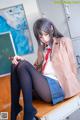 A woman sitting on top of a desk in a classroom.