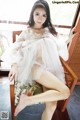 A woman in a white dress sitting on a chair.