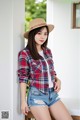 A woman wearing a hat and a plaid shirt posing for a picture.