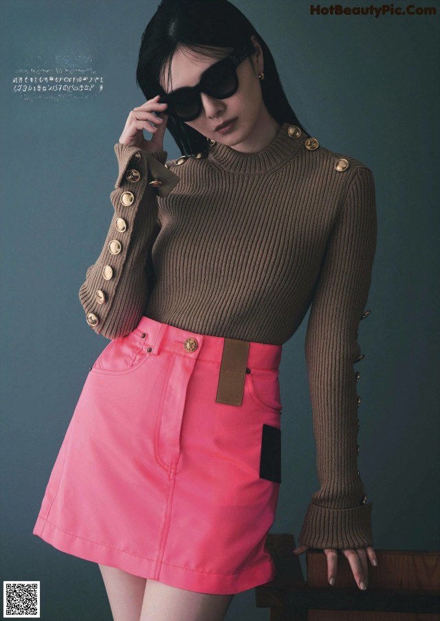 A woman in a pink skirt and a brown sweater.