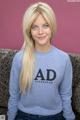 A woman sitting on a couch wearing a sweatshirt that says AD.