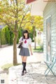 A woman in a school uniform is walking down a sidewalk.