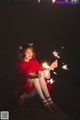 A woman sitting on the ground holding sparklers in her hands.