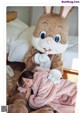 A little girl laying on a bed next to a stuffed bunny.