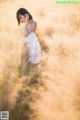 A woman in a white dress standing in tall grass.