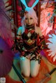 A woman with pink hair sitting on the ground with two swords.